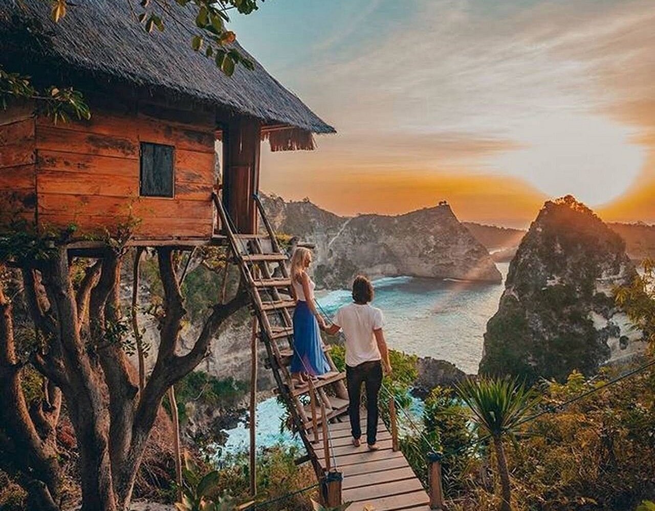 Couple watching sunset at the Atuh Beach treehouse viewpoint