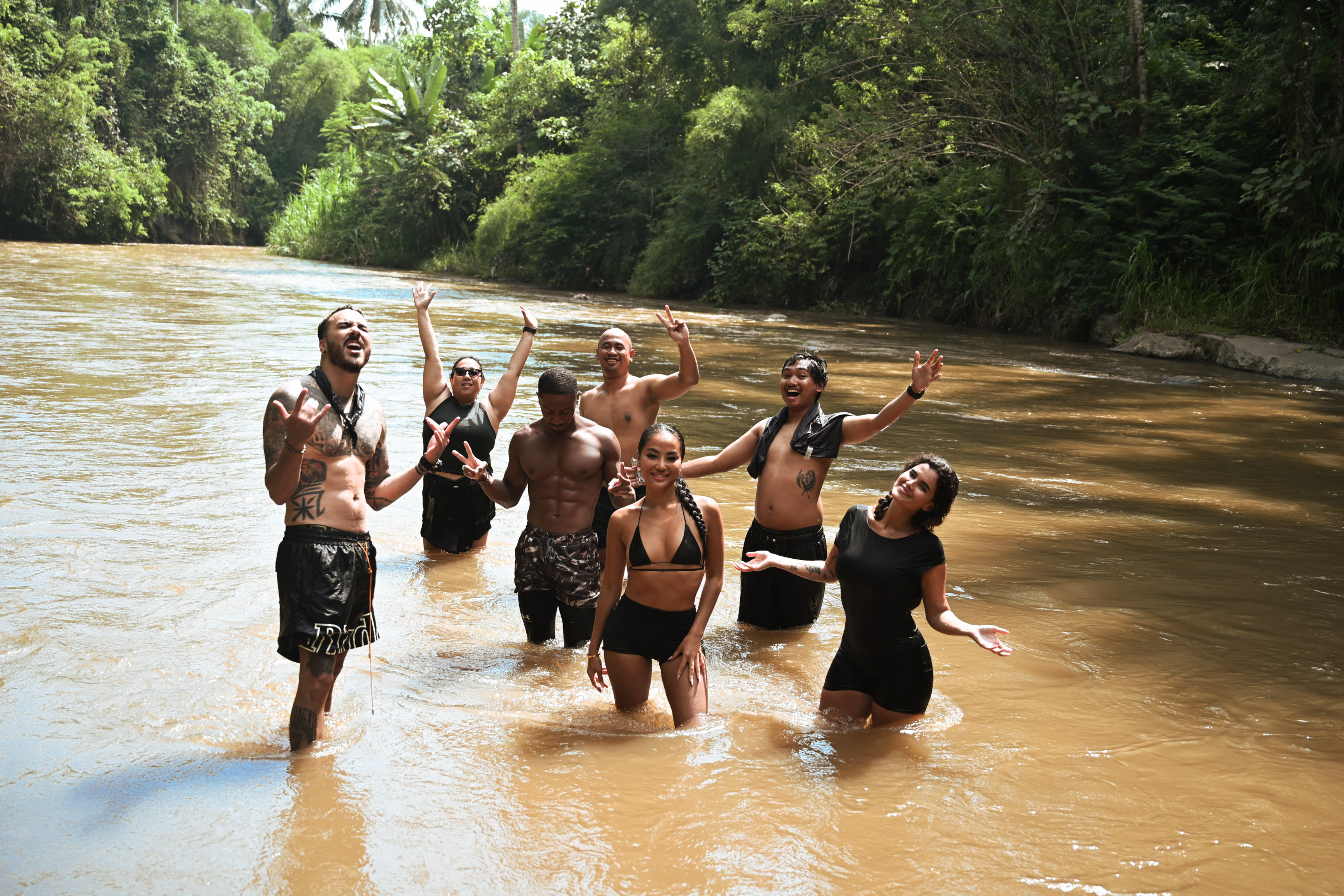 Group of riders celebrating waist-deep in the Ayung river after rafting