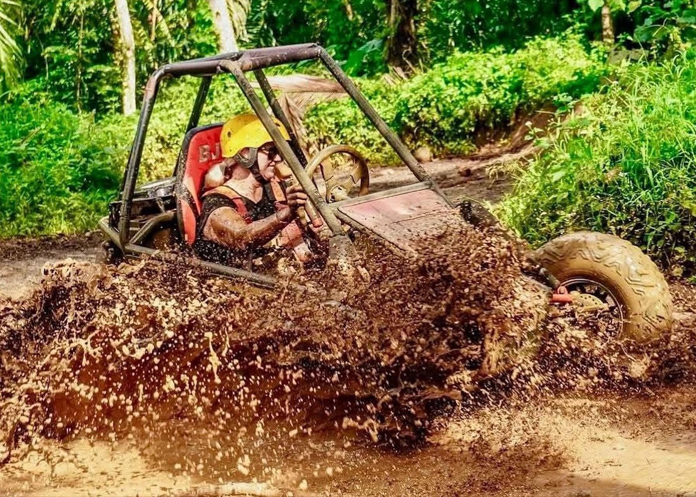 Pair of riders in muddy buggy on jungle adventure trail