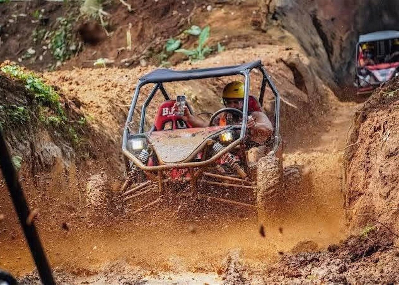 Buggy navigating muddy ravine track at speed