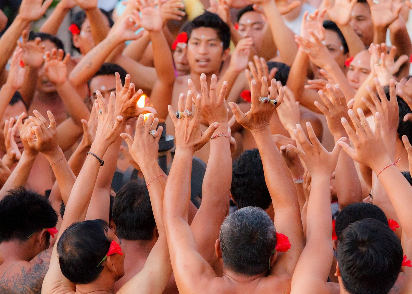 Kecak fire dance circle with raised hands at Uluwatu sunset